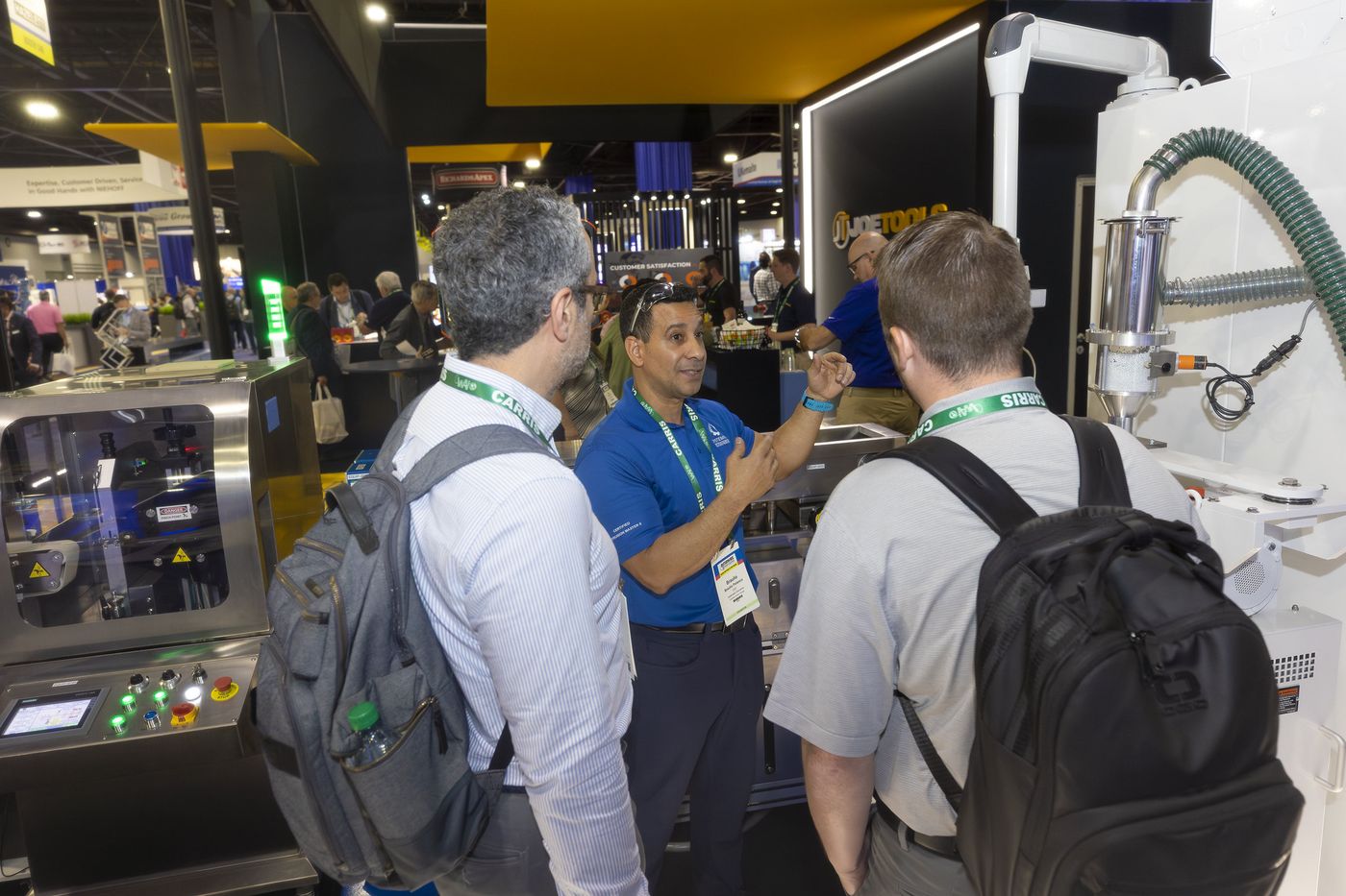 An exhibitor demonstrating equipment to visitors on the Interwire 2025 show floor